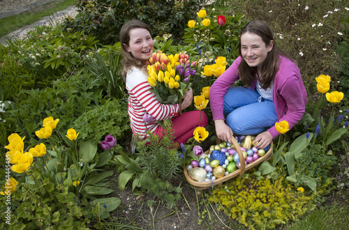 Easter egg hunt girls with chocolate eggs and Spring flowers