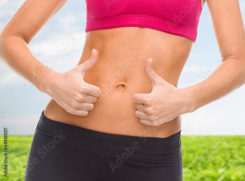 close up of female abs and hands showing thumbs up