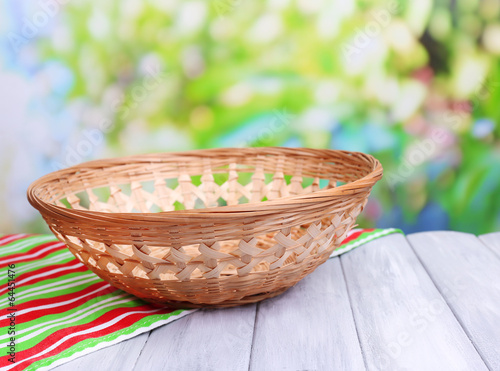 Empty wicker basket on wooden table  on bright background