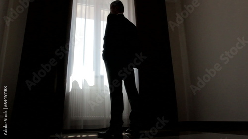 silhouette of stylish man in suit looking out the window
