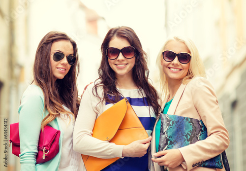 three smiling women with bags in the city