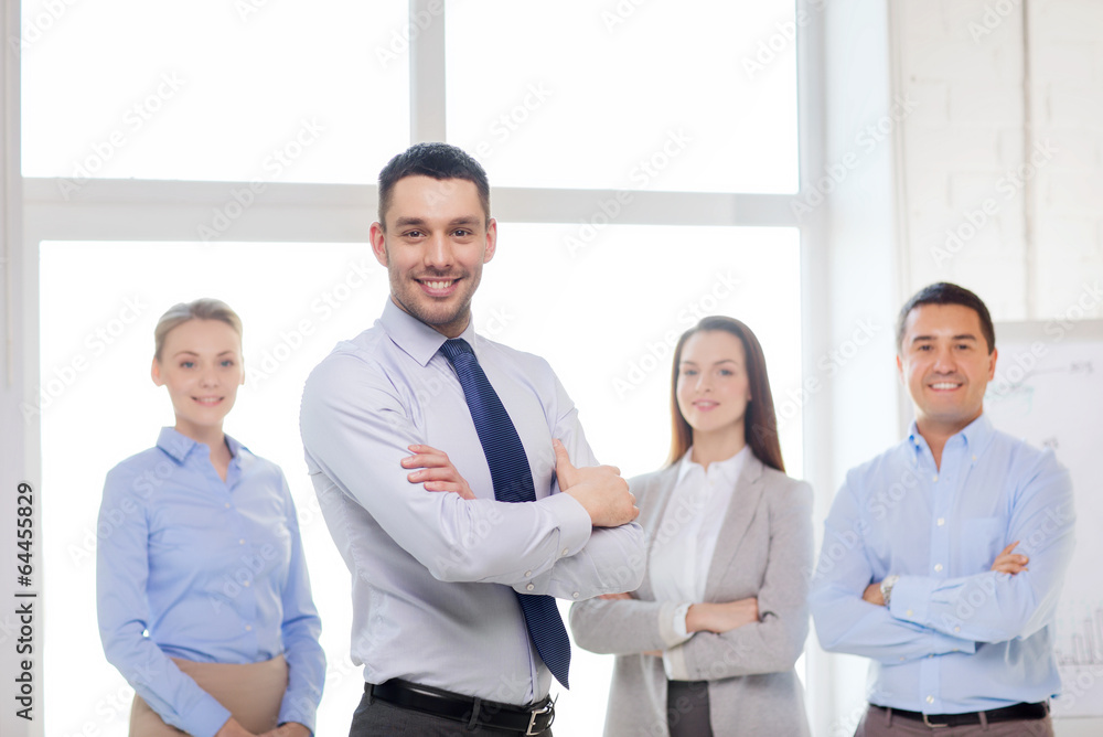 smiling businessman in office with team on back smiling businessman in office with team on back
