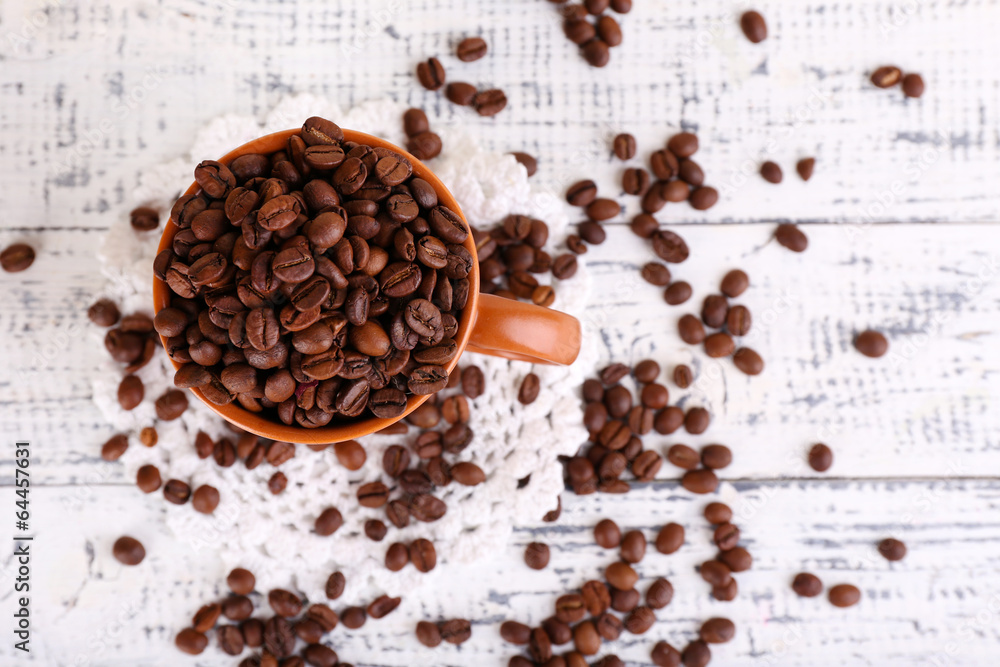Cup full of coffee beans on light wooden background Cup full of coffee beans on light wooden background