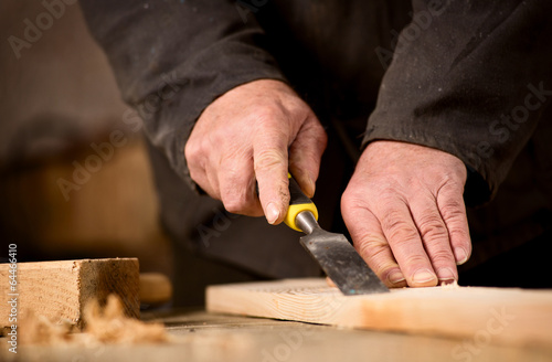 Carpenter using a chisel on a plank of wood