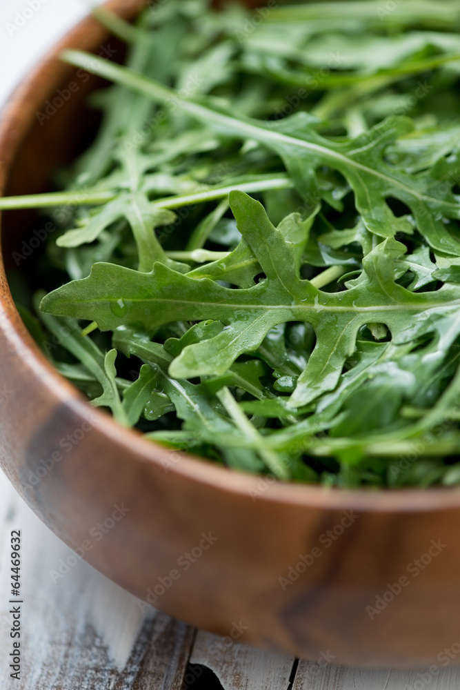 Fresh arugula in a wooden bowl, close-up, vertical shot Fresh arugula in a wooden bowl, close-up, vertical shot