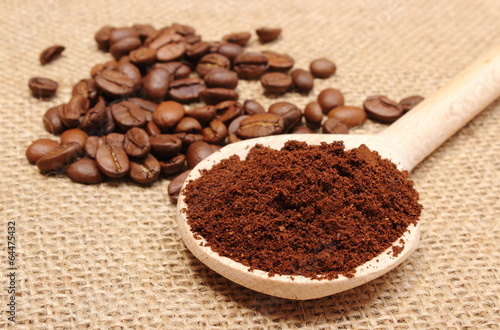Ground coffee on wooden scoop and grains in background