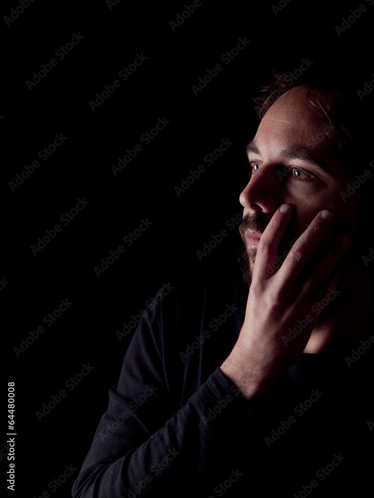 Low key image of a pondering bearded man