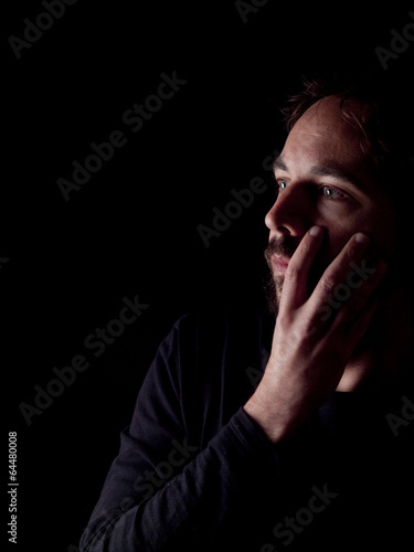 Low key image of a pondering bearded man