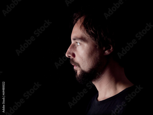 Low key image of the profile of a bearded man