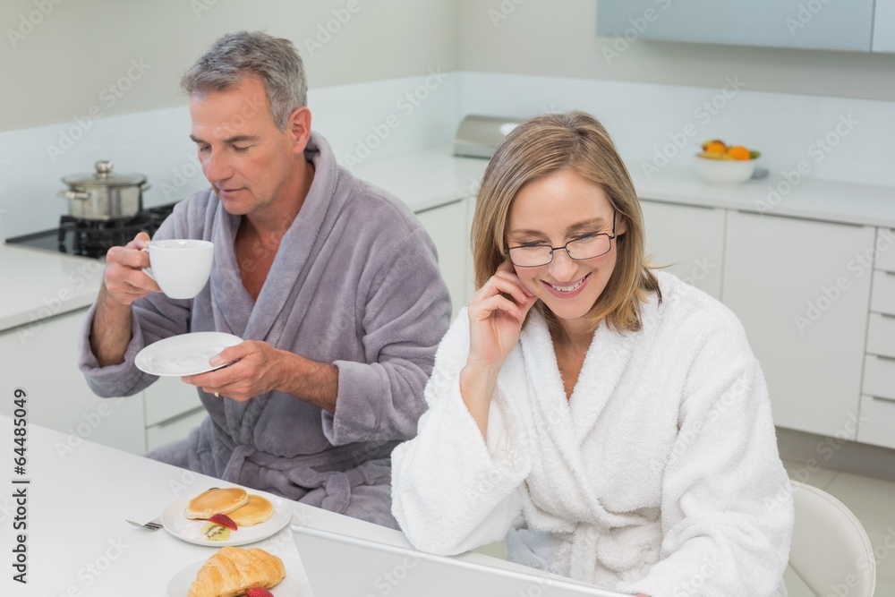 Obraz premium Couple in bathrobes having breakfast in kitchen