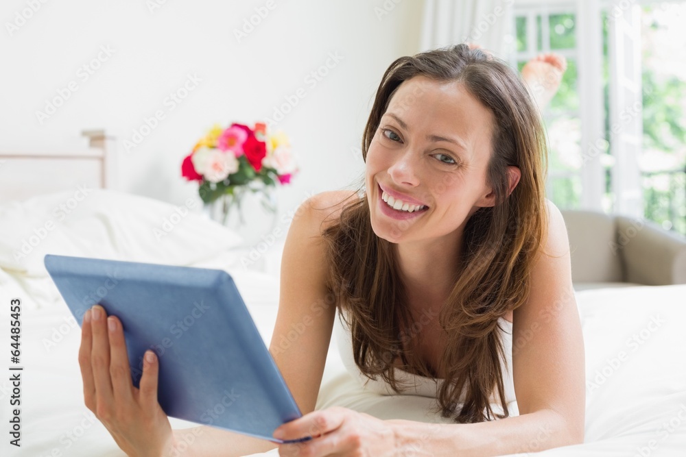 Smiling relaxed woman using digital tablet in bed Smiling relaxed woman using digital tablet in bed