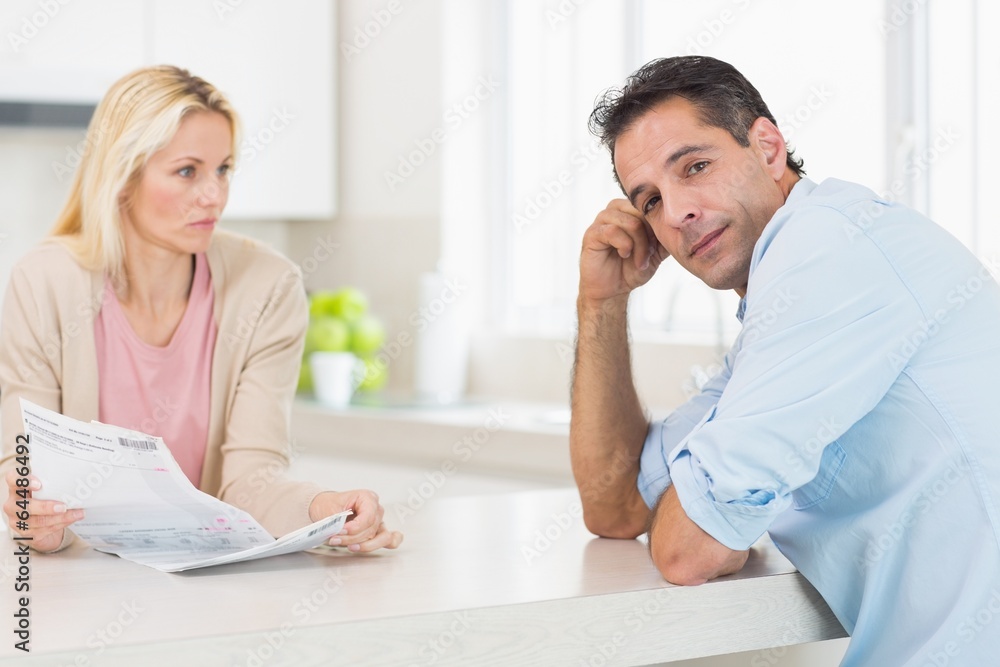 Obraz premium Upset couple with newspaper sitting in kitchen