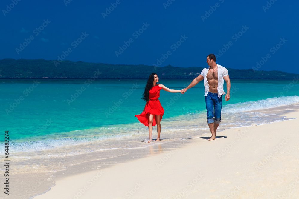 young loving couple walk through the tropical beach