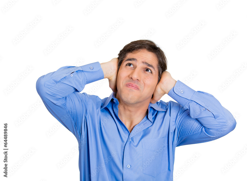Loud noise upstairs. Young man has a headache, covering ears Loud noise upstairs. Young man has a headache, covering ears
