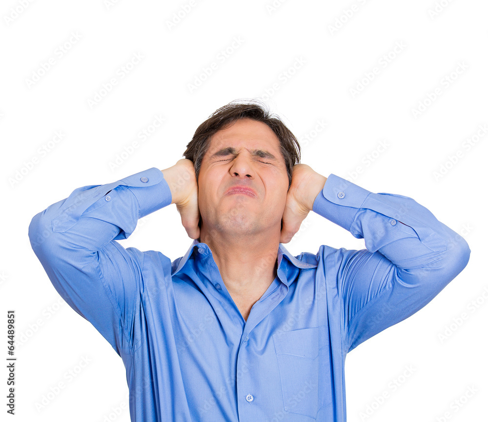 Loud noise upstairs. Young man has a headache, covering ears Loud noise upstairs. Young man has a headache, covering ears