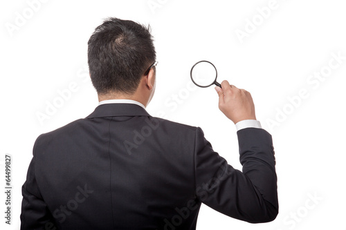 Back of Asian businessman with magnifying glass