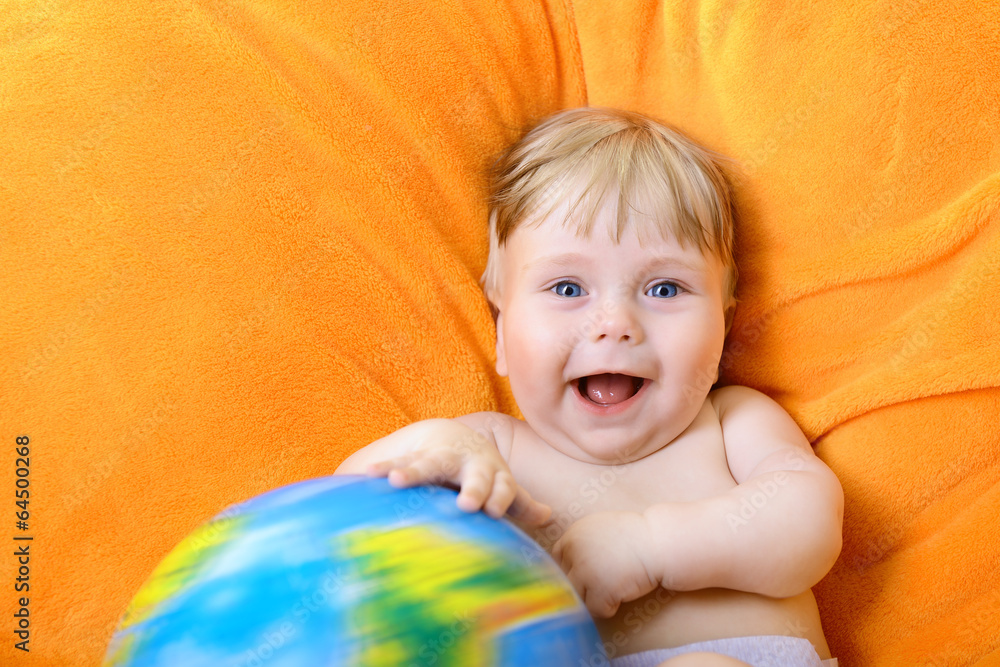 Happy baby playing with terrestrial globe on an orange plaid Happy baby playing with terrestrial globe on an orange plaid