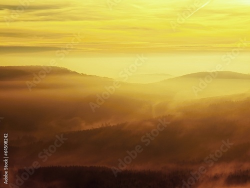 Autumn sunrise in a beautiful mountain of Bohemia. Hills in fog