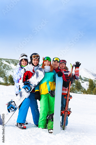 Cheerful friends standing with snowboards