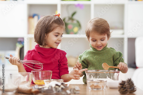 Two little children making cookies.