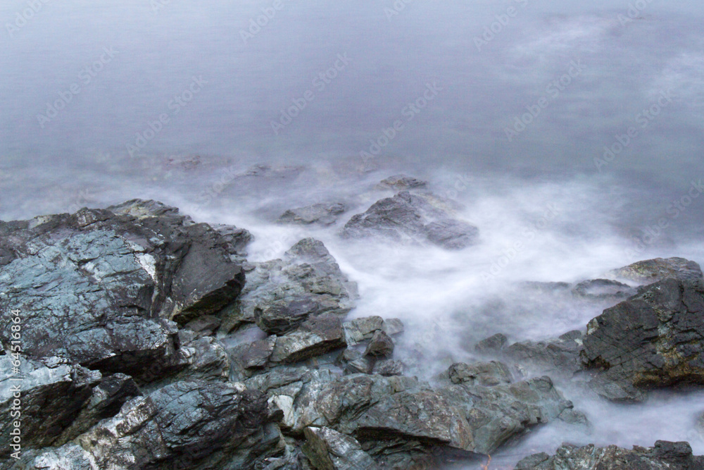 Eddy tide crashing against rocks on shoreline