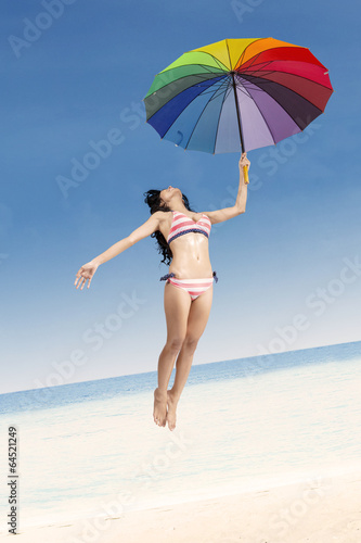 Woman in stripeed bikini jumping with umbrella © Creativa Images