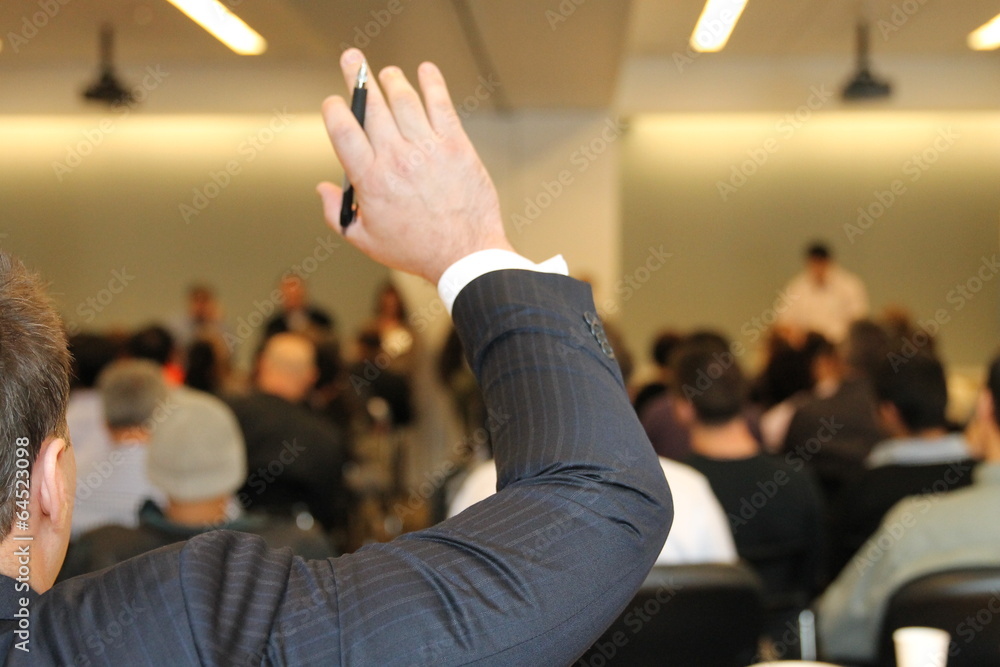 Businessman raising hand during business conference Businessman raising hand during business conference