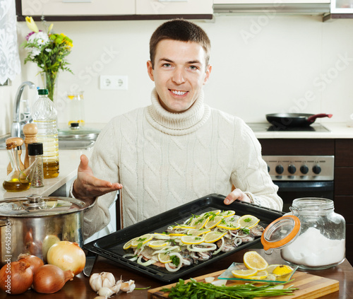 Smiling guy cooking  fish with lemon in  pan photo