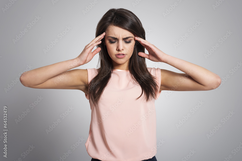 Woman with a migraine massaging her temples Woman with a migraine massaging her temples