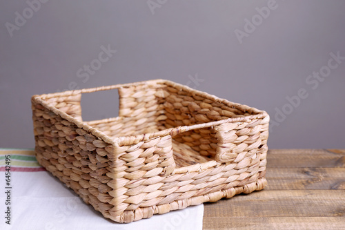 Empty wicker basket on wooden table  on dark background