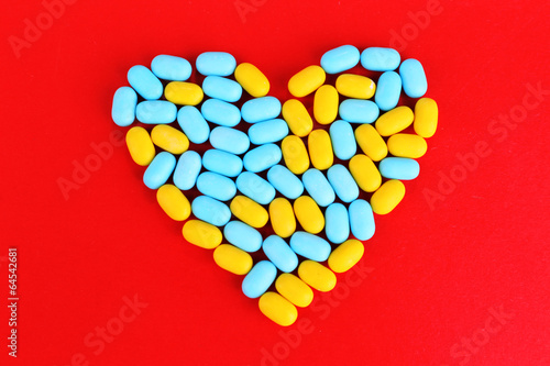 Heart of pills on red background