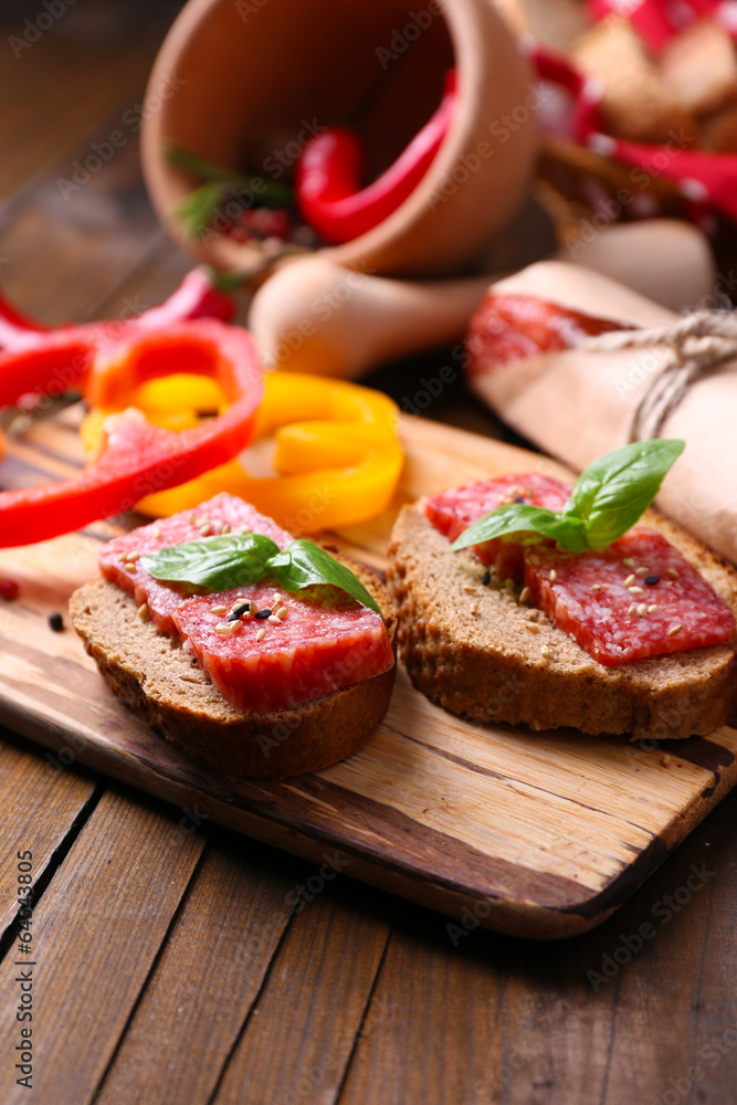 Composition with knife,  tasty sandwiches with salami sausage,