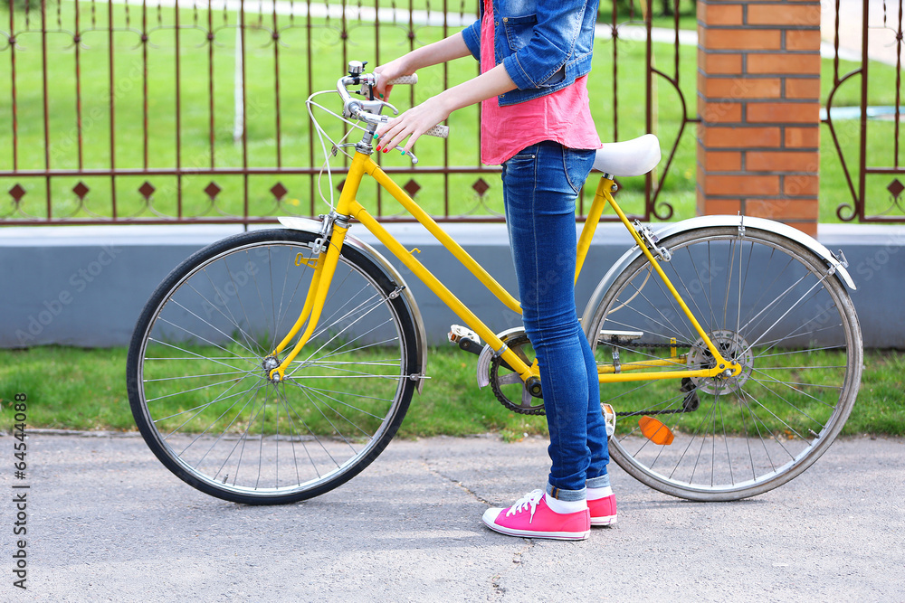 Naklejka premium Young woman with bicycle outdoors