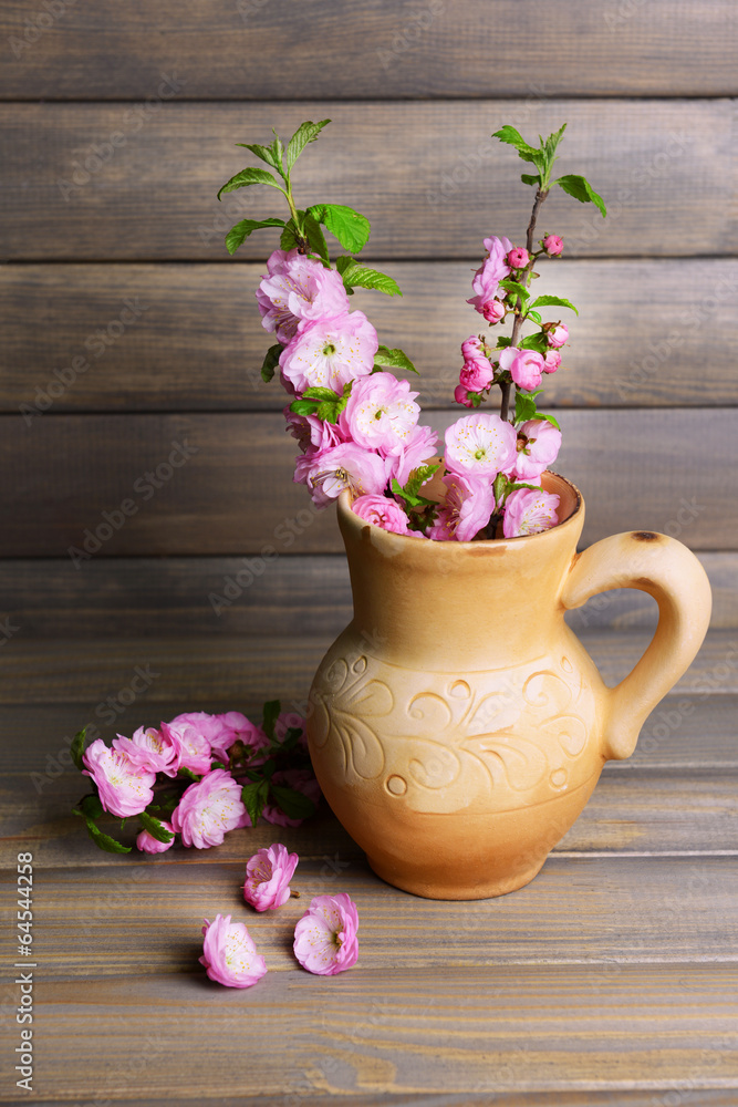 Beautiful fruit blossom in pitcher on table on grey background Beautiful fruit blossom in pitcher on table on grey background