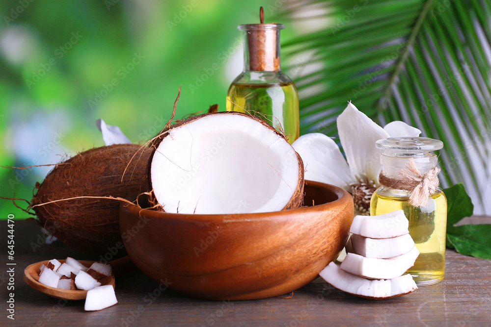 Coconuts and coconut oil on wooden table, on nature background Coconuts and coconut oil on wooden table, on nature background