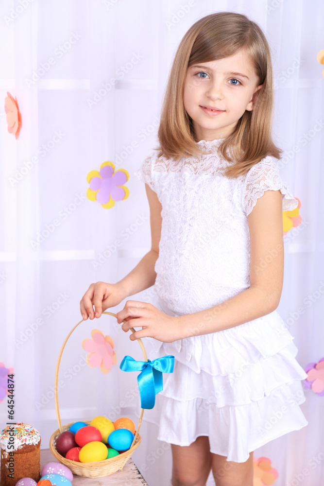 Beautiful small girl holding basket with colorful eggs