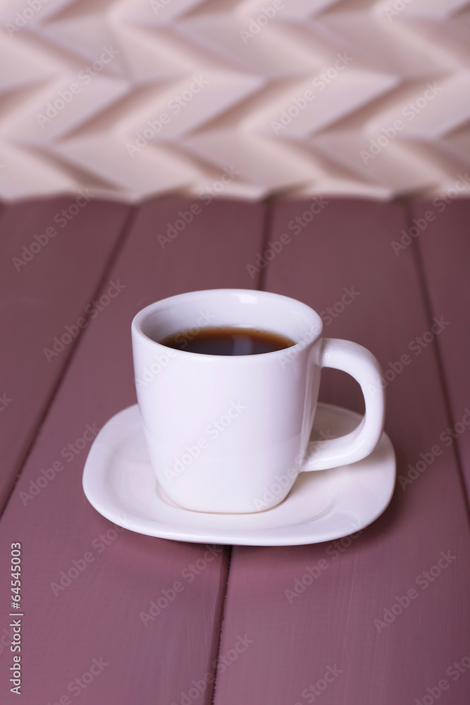 Cup of strong coffee on color wooden table, on light background