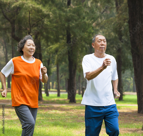happy senior couple jogging together in the park