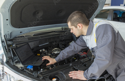 professional car mechanic in auto repair service with laptop