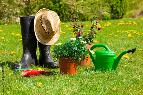Gardening tools and a straw hat on the grass in the garden