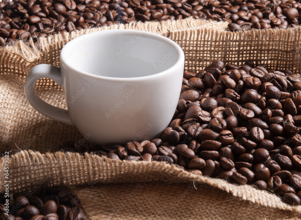 white cup with coffee on burlap background with beans white cup with coffee on burlap background with beans