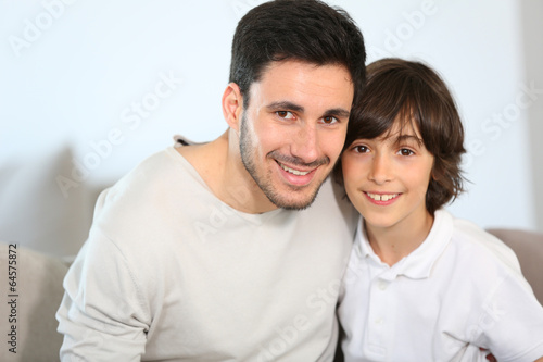 Portrait of father and son sitting in sofa © goodluz