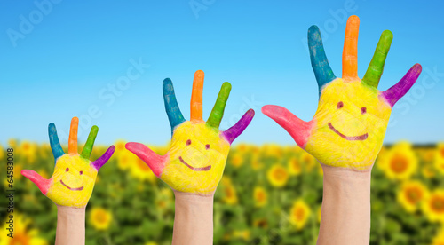 Three painted hands of family on sunflowers field
