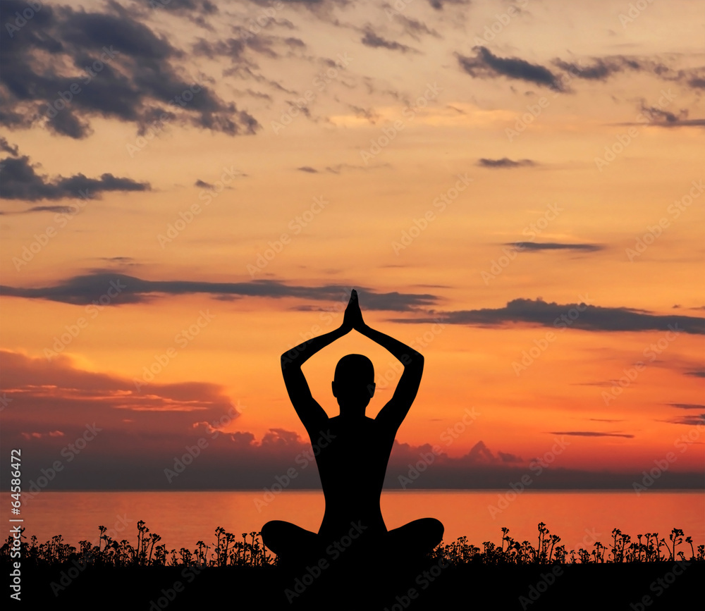 Silhouette of a woman meditating on a sunset