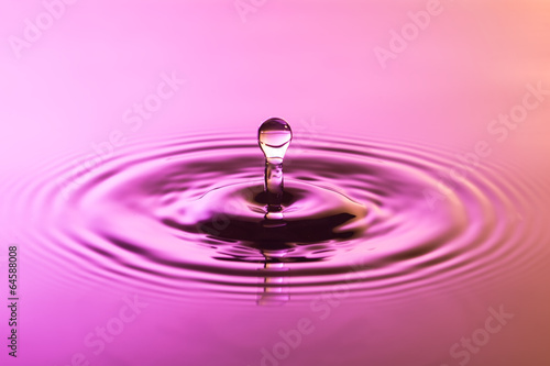 Water drop close up with concentric ripples colourful pink and y