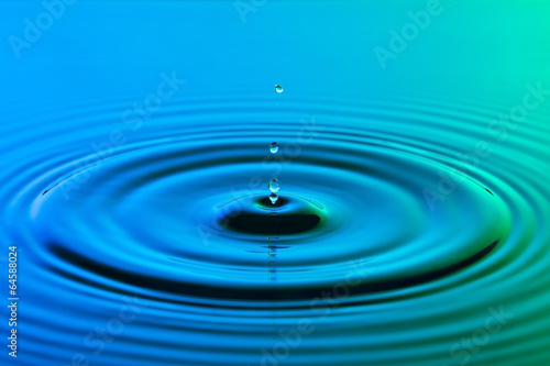 Water drop close up with concentric ripples colourful blue and g