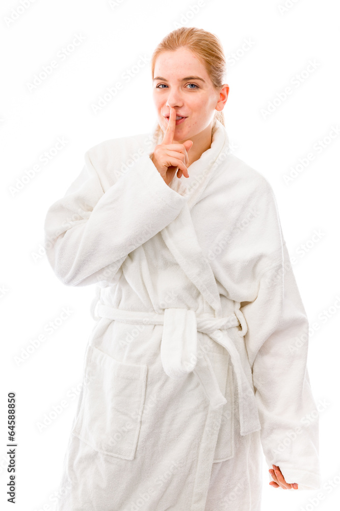 Young woman standing in bathrobe with finger on lips Young woman standing in bathrobe with finger on lips
