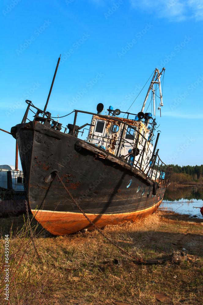 broken rusty ship standing on the river bank