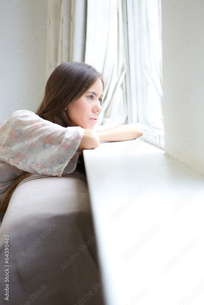 Young woman relaxing by window at home Young woman relaxing by window at home