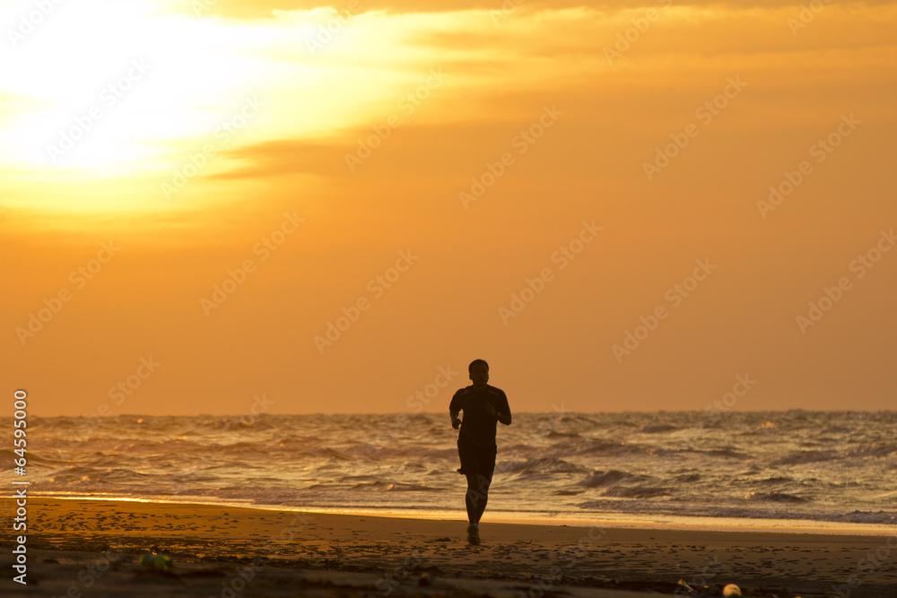 A man running on the beach at sunset